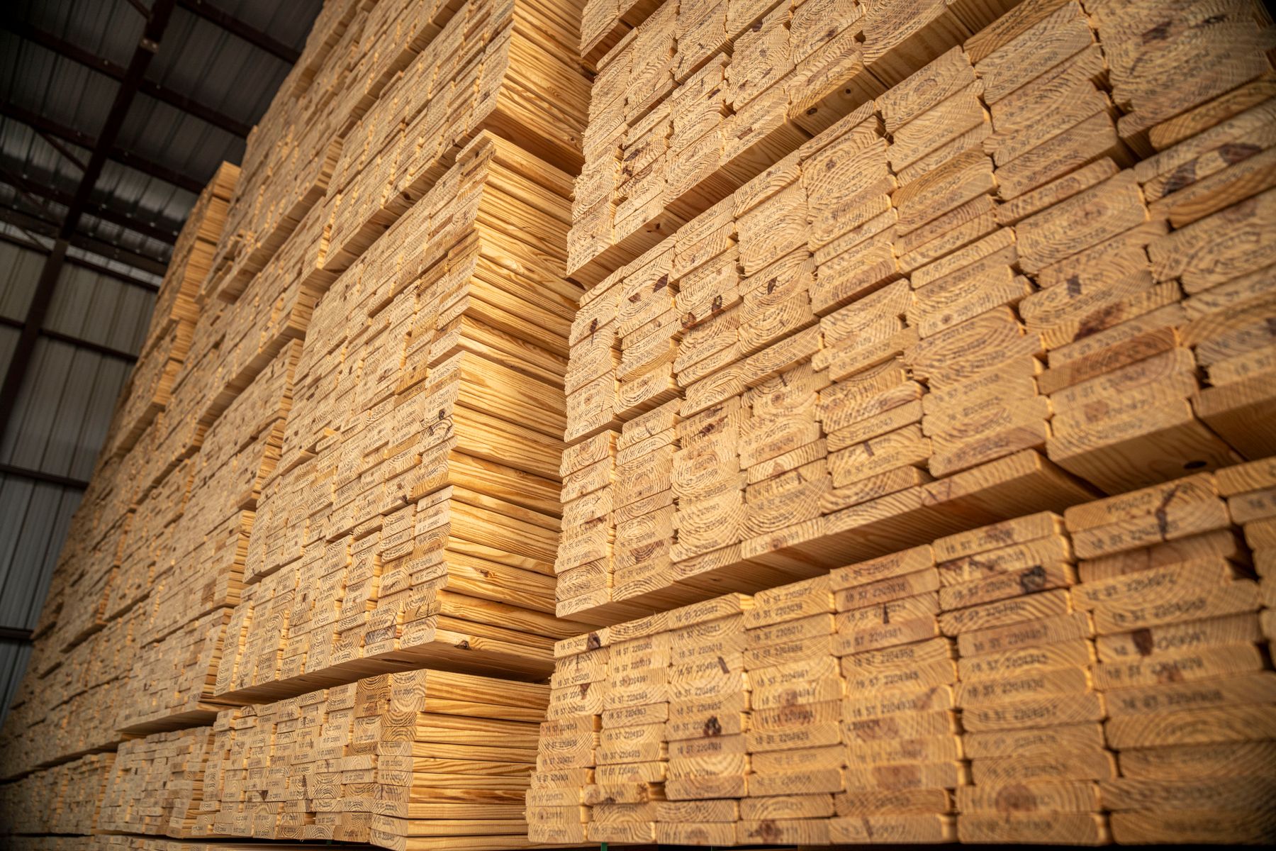 Large stacks of lumber stored in an industrial warehouse